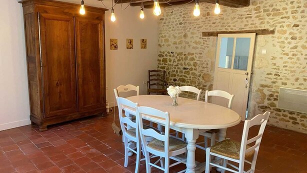 Un comedor con una mesa redonda, sillas blancas y un aparador de madera.