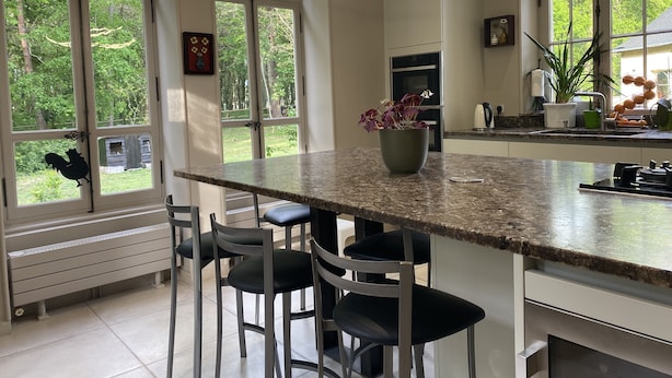 A modern kitchen with a large island, bar stools, and a view of the outdoors. - Château de la Coudraie Sarthe 72560 (Changé)