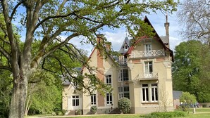 A large, historic building with multiple stories, a prominent tower, and a well-maintained lawn. - Château de la Coudraie Sarthe 72560 (Changé)