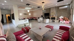 A spacious living area with a sofa set, a coffee table, and a TV. - The Lemon Tree (Ainjohra)