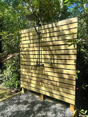 A wooden fence with horizontal slats, a metal structure attached to it, and a gravel area in front.