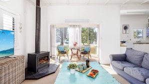 Een gezellige woonkamer met een open haard, een eethoek met stoelen, een bank en een keukenhoek.