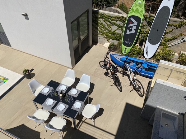An outdoor patio with a table set for dining, surrounded by white chairs.