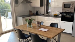 A modern kitchen with white cabinets, a wooden dining table, black chairs, and a large window. - Modern Villa with Pool & Sea View-40m to the Beach (Lun)