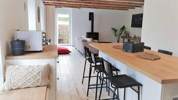 Une cuisine moderne avec un bar en bois, des chaises noires et un mur en pierre.