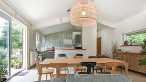 Une cuisine spacieuse avec une grande table à manger, des appareils modernes et une vue sur le jardin.