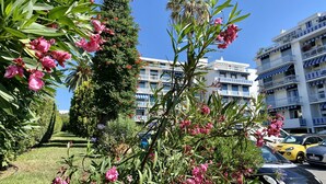 Un immeuble doté de balcons, un ciel dégagé et des voitures garées.