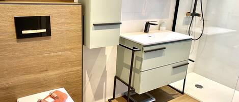 A modern bathroom with a toilet, sink, and shower area.