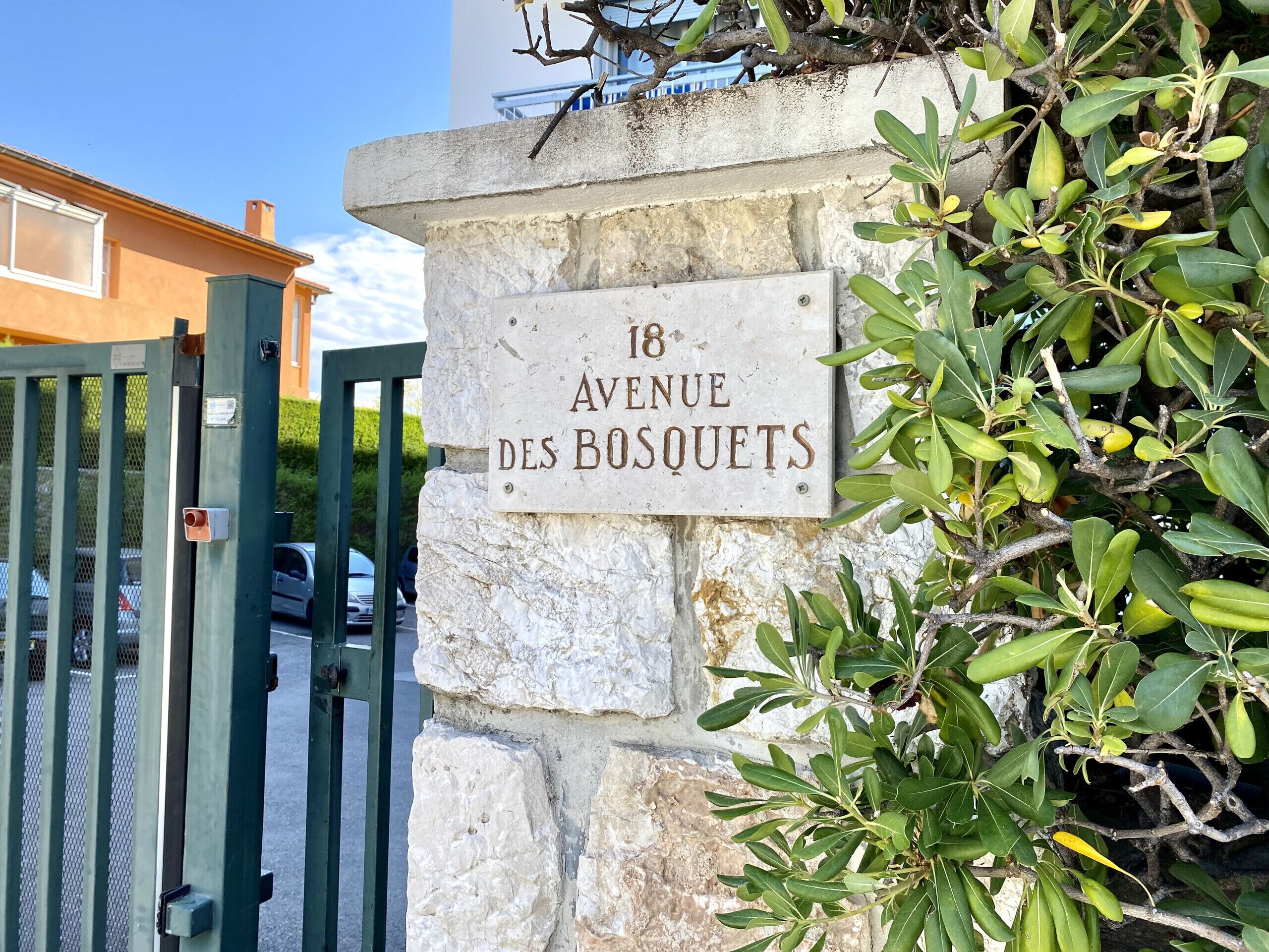 Et vejskilt med teksten "18 Avenue des Bosquets" monteret på en stenvæg.
