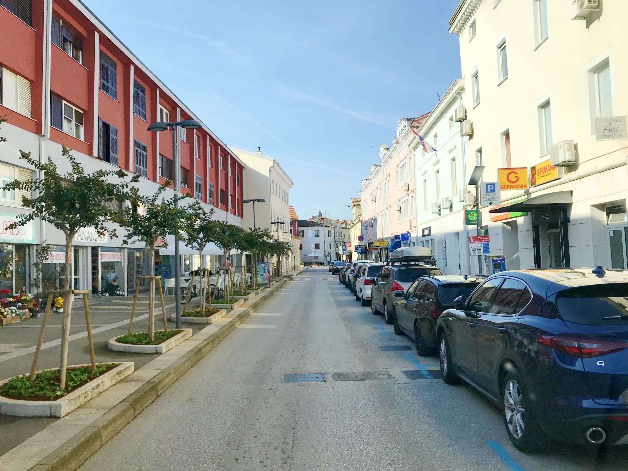 Eine Straße mit geparkten Autos und Gebäuden mit Geschäften.
