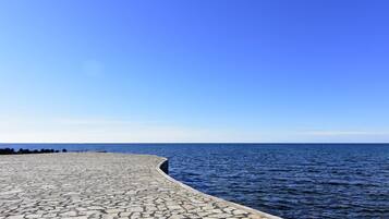 Una passeggiata lungomare lastricata in pietra con vista libera sul mare sotto un cielo azzurro.
