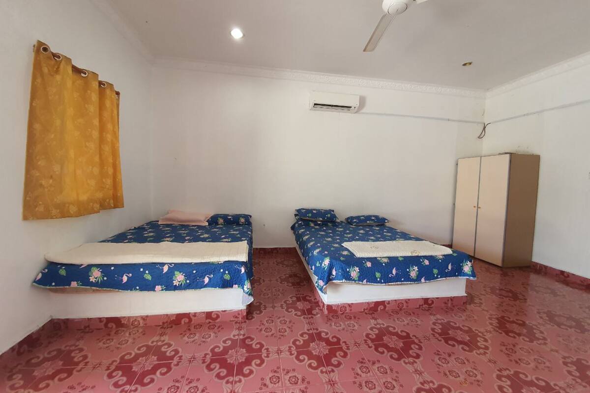 Una habitación con dos camas, ventilador de techo, aire acondicionado y armario.