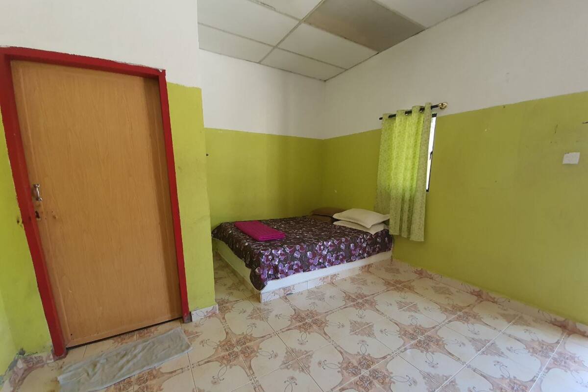 Un dormitorio con cama, una puerta y una ventana con cortinas.