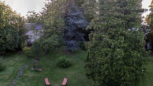Een tuin met een prieel, gazon en verschillende bomen.