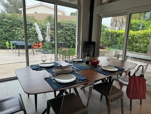 Enjoy al fresco dining in a serene setting with a large table for four, comfortable seating, and a view of lush greenery.