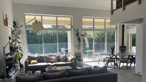 A modern living room with a large sofa, a dining table, and a fireplace.
