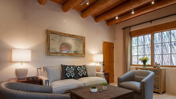 Un salon chaleureux avec un canapé, des fauteuils, une table basse et un tableau accroché au mur.