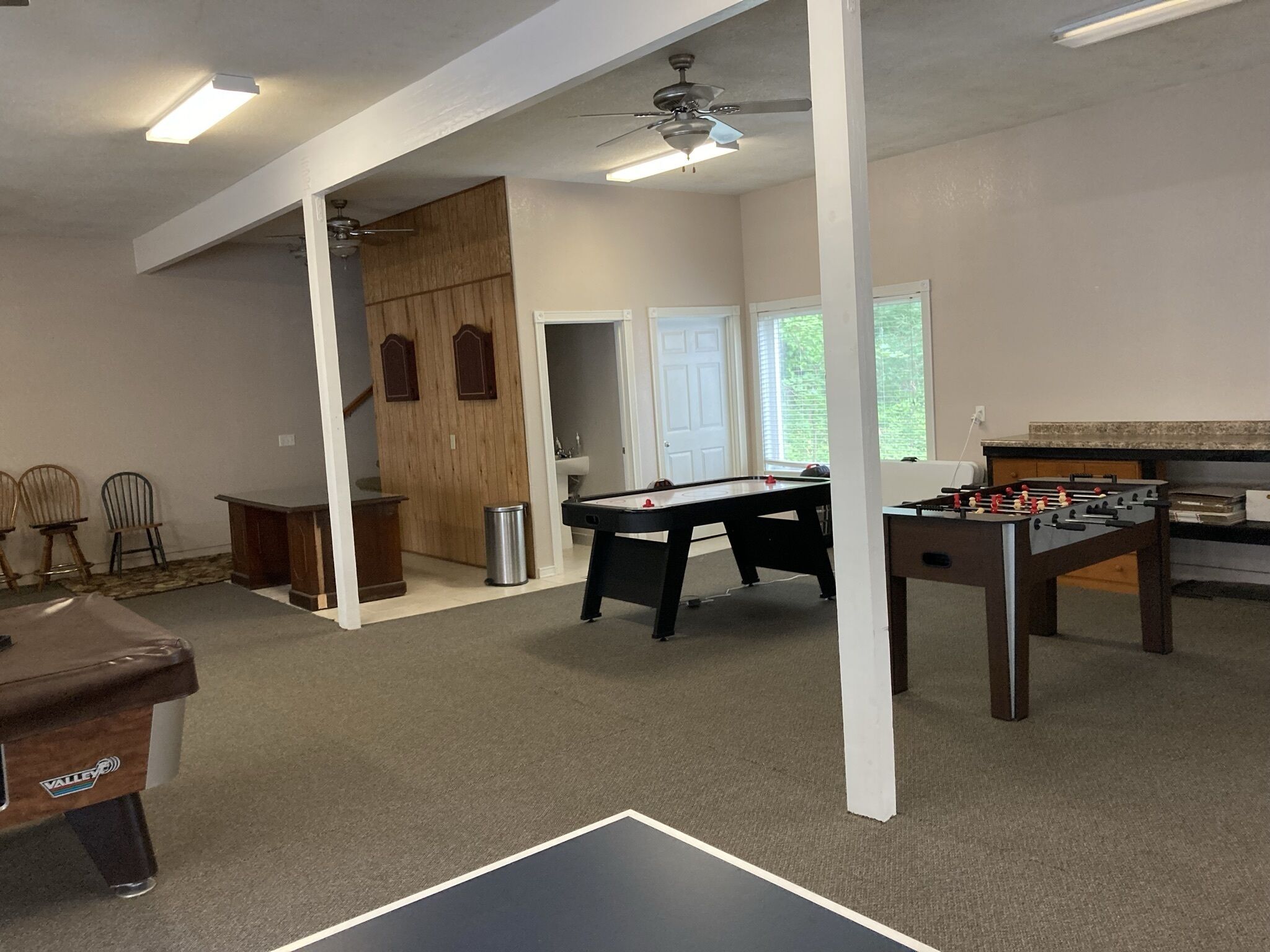 Een ruime kamer met een tafelvoetbaltafel, een poezenpotje en een pingpongtafel.