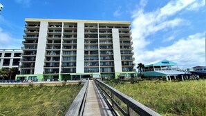 Ein mehrstöckiges Hotel mit Balkonen, einer Holzpromenade, die zum Eingang führt, und einem wolkenlosen, blauen Himmel.