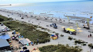 Ein Strand mit einem Pier im Hintergrund, Strandstühlen und einigen Personen.