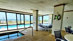 Ein Poolbereich im Innenbereich mit Blick auf den Strand, einem Billardtisch und Stühlen.