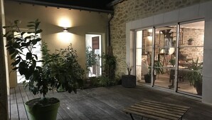 Eine überdachte Terrasse mit Holzboden, Blumentöpfen und einer Bank.