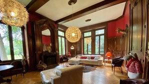 Ein geräumiges Wohnzimmer mit Kamin, einer Sofagarnitur und einer großen Chandelier.