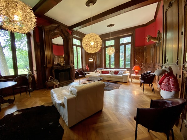 Un salon spacieux avec une cheminée, un ensemble de canapés et un grand lustre.