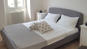 A neatly arranged bedroom with a bed, bedside tables, a lamp, and a window. - The Baions House (Roma)