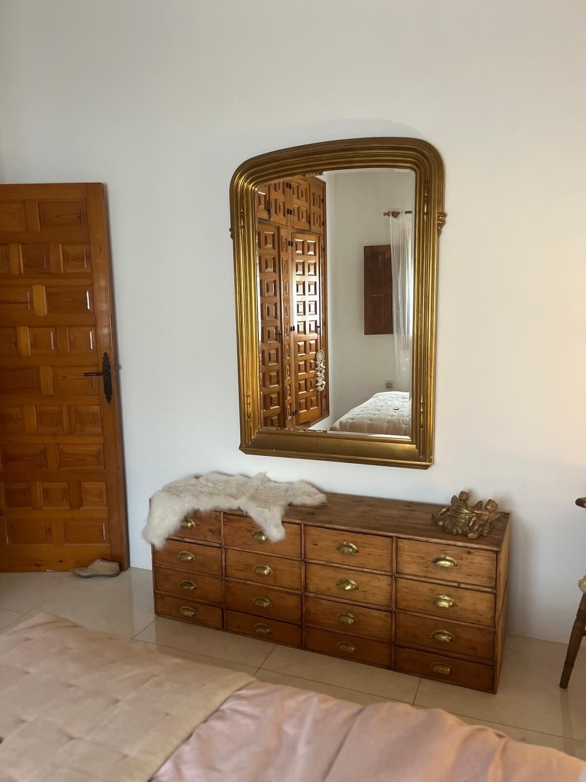 A room with a wooden dresser, a large mirror, and a door.