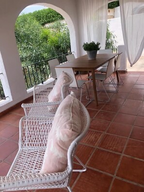 A patio with white wicker chairs, a wooden table, and a potted plant. - <br>CASA LIMON - Family Villa with private pool (Moraira)
