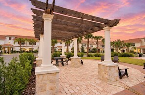 A covered patio area with stone columns, picnic tables, and outdoor seating.