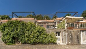 A building with a metal framework, a covered outdoor seating area, and a large bush in front. - Casa Filippo by Feeling Italy (Sant'Agata sui Due Golfi)