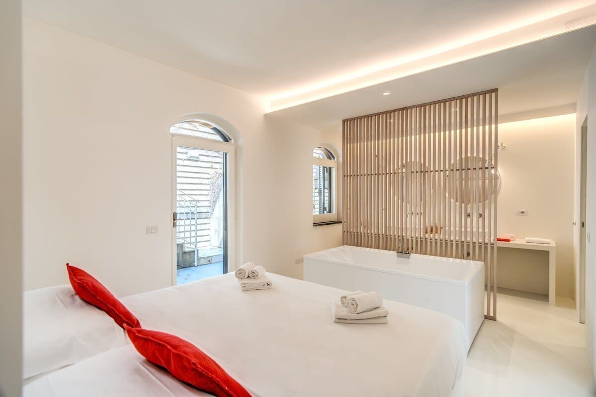 Una habitación de hotel moderna con una cama grande, una bañera y una ventana con persianas.
