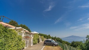 A hillside property with a car parked in front, a gate, and a view of a mountain in the distance. - Casa Filippo by Feeling Italy (Sant'Agata sui Due Golfi)
