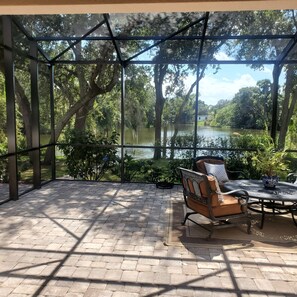 A covered patio with a view of a lake, furnished with a table and chairs. - Centrally located waterfront home (Merritt Island)