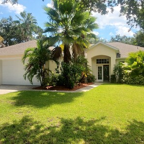 A single-story house with a front yard, a palm tree, and a well-maintained lawn. - Centrally located waterfront home (Merritt Island)