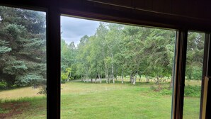 Una habitación con un ventanal grande que da a un jardín con árboles.