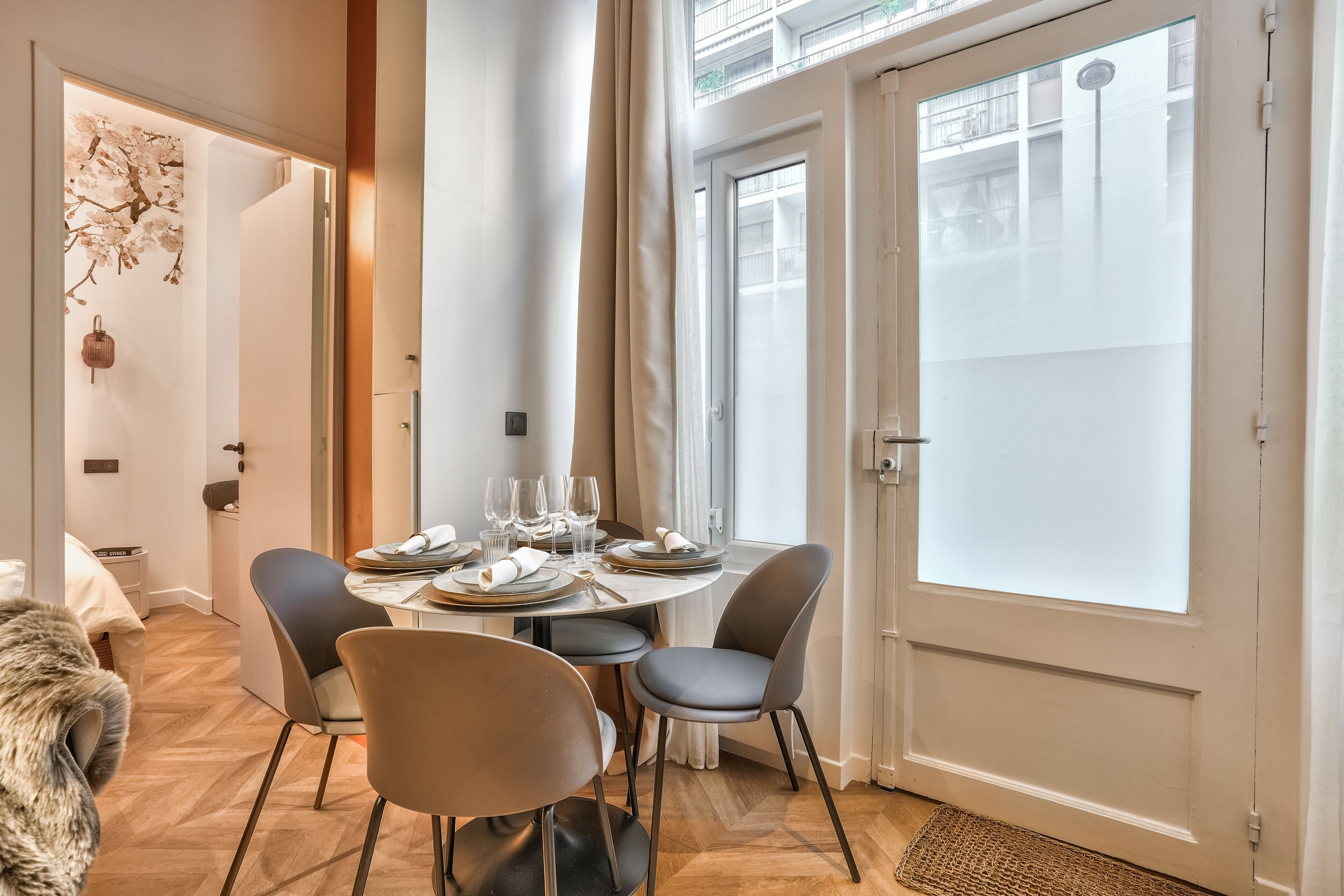 Un coin repas avec une table ronde dressée pour quatre personnes, entourée de chaises modernes.