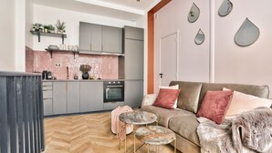 A modern kitchen with grey cabinets, a herringbone floor, and a grey sofa with a fur throw. - NEW! Eiffel Tour Splendid 2BR apt in Paris (Paris)