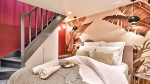 A bedroom with a bed, pillows, a bedside table, a lamp, a wall mural, and a staircase. - NEW! Eiffel Tour Splendid 2BR apt in Paris (Paris)