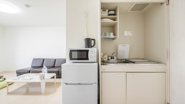 A compact living space with a kitchenette, a sofa, a coffee table, and a refrigerator.