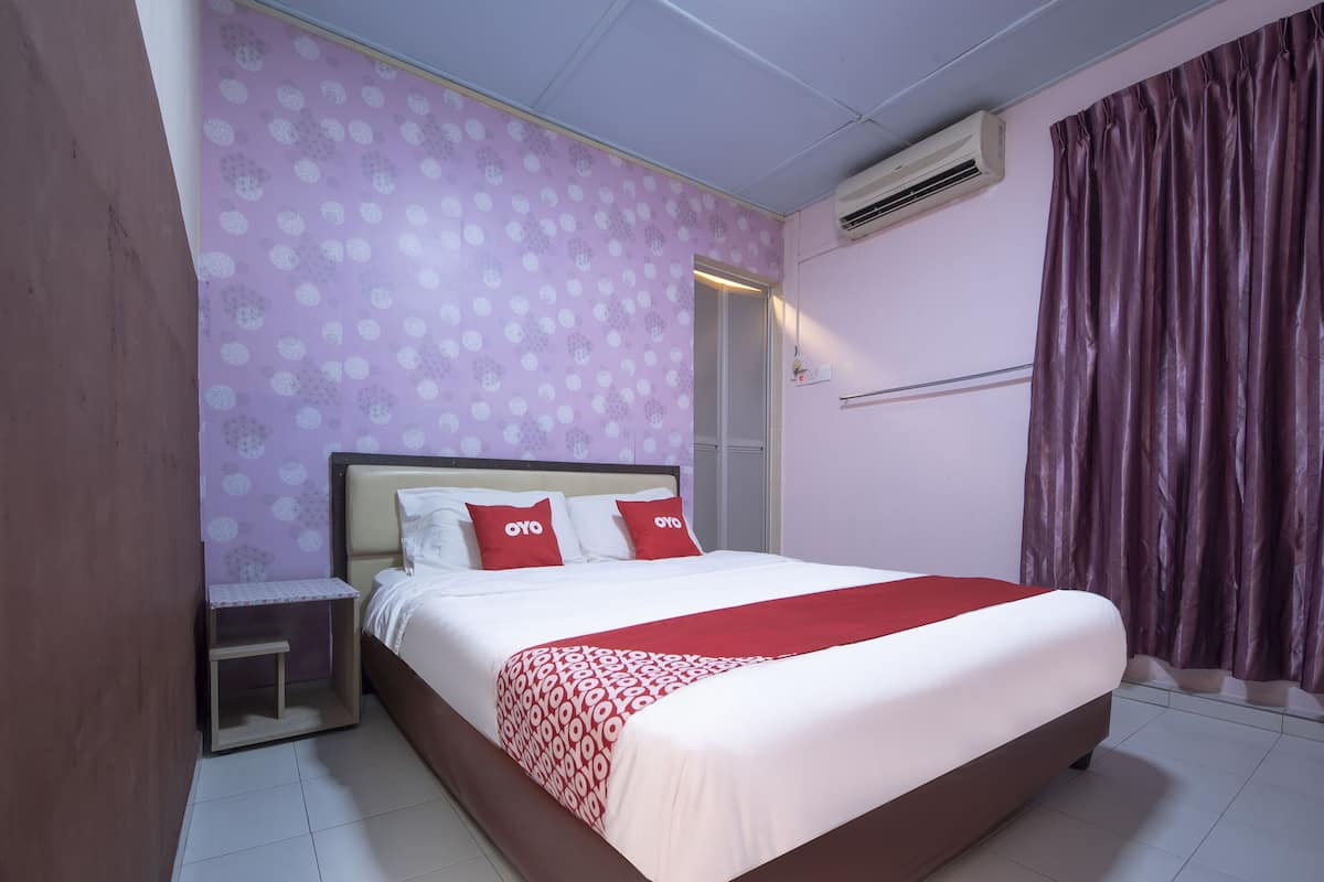 Une chambre à coucher comprenant un lit, une table de chevet, une fenêtre avec des rideaux et un appareil de climatisation.