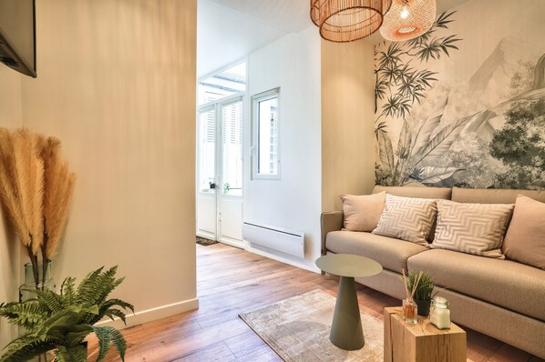 A modern living room with a sofa, a coffee table, and a wall mural. - NEW ! Eiffel Tour Superb 1BR Apt in Paris (Paris)