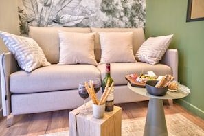 A cozy living room with a sofa, a small wooden table with a bottle of wine, glasses, and snacks. - NEW ! Eiffel Tour Superb 1BR Apt in Paris (Paris)