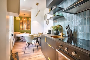 A modern kitchen with a large stove, a sink, and a dining area with a table and chairs. - NEW ! Eiffel Tour Superb 1BR Apt in Paris (Paris)