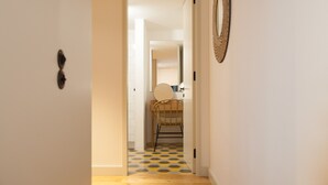 A hallway with a patterned floor, a chair, and a mirror on the wall. - FLH Intendente Blue Flat with Balcony (Lisbon)