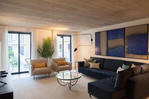Una sala de estar moderna con sofá, sillón, mesa de centro y un amplio ventanal.