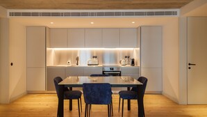 A modern kitchen with a central island, built-in appliances, and a dining area with a glass table and chairs. - FLH Intendente Blue Flat with Balcony (Lisbon)