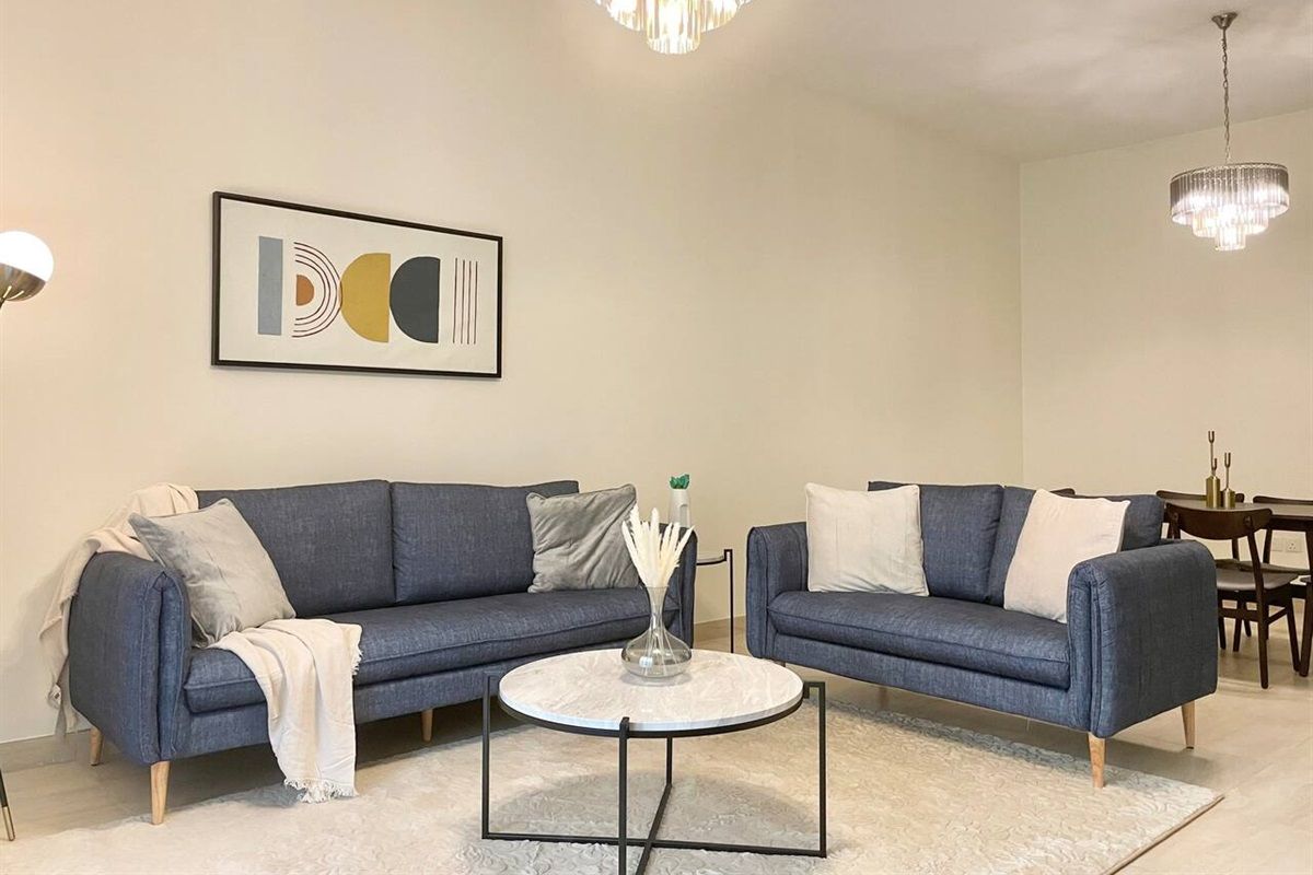 Un salon moderne avec deux canapés, une table basse et un lustre.